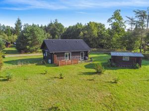 a log cabin in a field with a house at Holiday Home Barni - 7km from the sea by Interhome in Ebeltoft