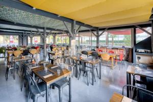 a restaurant with wooden tables and chairs and windows at Camping Mobil Home 6 Pers Rivage des Landes Piscine Landes in Aureilhan