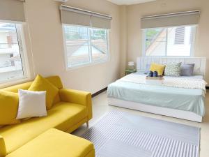 a bedroom with a bed and a couch and windows at Everything Within Minutes House in Bangkok