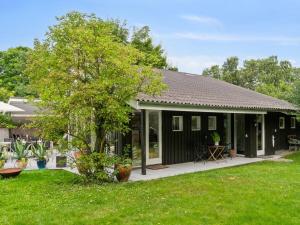 a black house with a garden and a tree at Holiday Home Ivar - 150m from the sea by Interhome in Neksø