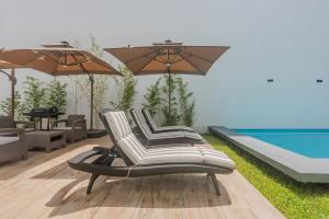 un gruppo di sedie e ombrelloni accanto a una piscina di Malibu Residential 3BD - Lia a Cozumel