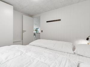 a white bedroom with a large white bed at Holiday Home Wilgrib - 50m from the sea by Interhome in Rønne +23 photos
