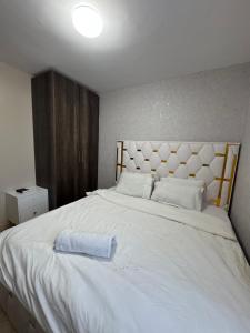 a white bed with a blue towel on it at Epic brownstone Apartments Phase 1 in Nairobi +16 photos