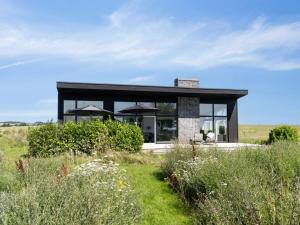 a black house in a field with grass at Holiday Home Bæver - 200m from the sea by Interhome in Knebel