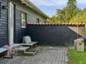 eine Terrasse mit einer Bank neben einer schwarzen Wand in der Unterkunft Holiday Home Frede - 1km from the sea by Interhome in Dronningmølle