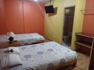 a room with two beds and a bathroom at Hotel Jophachi in Camaná