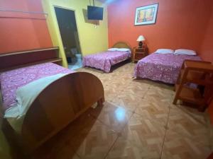 two beds in a room with pink sheets at Hotel Jophachi in Camaná +1 photo