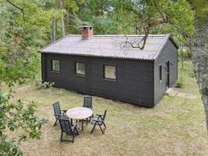 eine kleine schwarze Hütte mit einem Tisch und Stühlen in der Unterkunft Holiday Home Andresine - 1-3km from the sea by Interhome in Rørvig + 16 Fotos