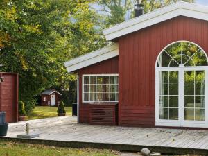 a red shed with a white door and a deck at Holiday Home Galathea - 175m from the sea by Interhome in Nykøbing Sjælland