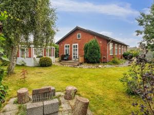 a red brick house with a yard with a bench at Holiday Home Saja - 550m from the sea by Interhome in Børkop
