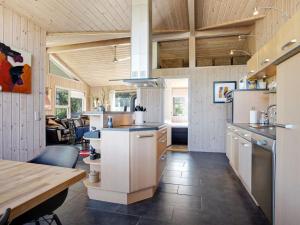 a kitchen with white cabinets and a wooden ceiling at Holiday Home Frido - 500m from the sea by Interhome in Sæby +20 photos