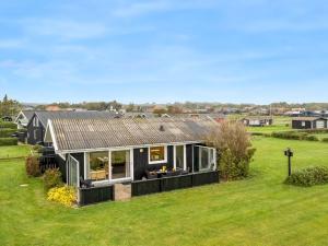 a small black house on a green field at Holiday Home Snioulf - 10m from the sea by Interhome in Sæby