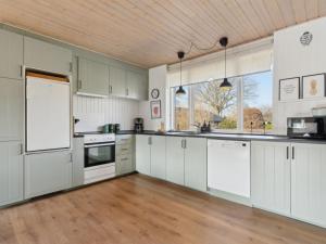 a large kitchen with white cabinets and a wooden floor at Holiday Home Vemund - 500m from the sea by Interhome in Aabenraa