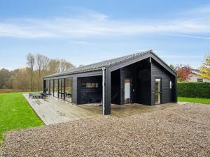 a black house with a deck in a field at Holiday Home Ehmi - 750m from the sea by Interhome in Haderslev