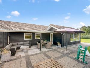 a patio with a couch and an umbrella at Holiday Home Billa - 450m from the sea by Interhome in Blåvand