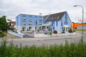een blauw gebouw aan de kant van een weg bij Hotel Vater Rhein in Wörth am Rhein