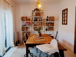 ein Esszimmer mit einem Holztisch und weißen Stühlen in der Unterkunft Spacious 3BR - Fireplace, garden studio and surfboards in Aroeira
