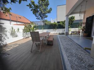 eine Holzterrasse mit einem Tisch und Stühlen darauf in der Unterkunft Spacious 3BR - Fireplace, garden studio and surfboards in Aroeira