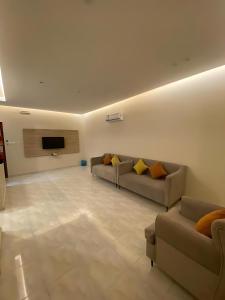 a living room with couches and a flat screen tv at شقق جوهرة الخميس للشقق المخدومة in Khamis Mushayt