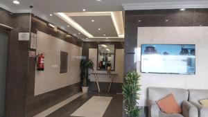 a lobby with a couch and a tv on a wall at شقق جوهرة الخميس للشقق المخدومة in Khamis Mushayt