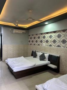 a bedroom with a large bed with white sheets and pillows at Hotel Gokul in Ahmedabad