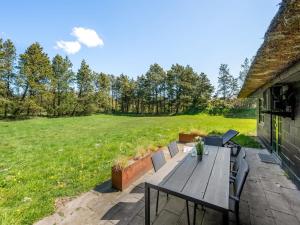 a patio with a wooden table and chairs and a field at Holiday Home Matilda - 1-6km from the sea by Interhome in Ulfborg +28 photos