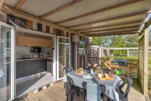 a patio with a table and a kitchen on a deck at Camping maeva Respire Le Village Perrosien in Perros-Guirec