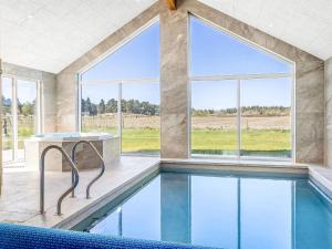 an indoor pool with a table and windows at Holiday Home Sönke - 4km from the sea by Interhome in Tagholm