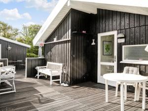 a wooden deck with a white table and chairs at Holiday Home Gonda - 2km from the sea by Interhome in Saltum
