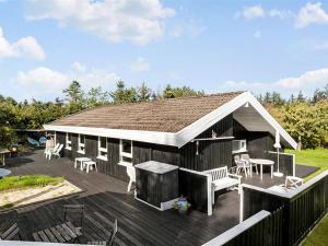 a house with a deck with a table and chairs at Holiday Home Gonda - 2km from the sea by Interhome in Saltum