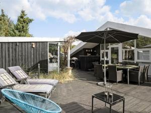 a patio with chairs and an umbrella on a deck at Holiday Home Gonda - 2km from the sea by Interhome in Saltum