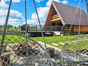 a log cabin with a porch and a swing at Chalet Tomina Koliba Lika by Interhome in Lovinac +26 photos