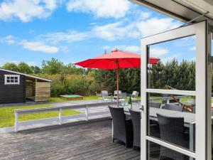 a patio with a red umbrella on a deck at Holiday Home Falki - 320m from the sea by Interhome in Otterup +20 photos
