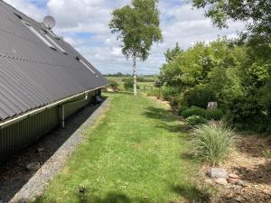 a yard next to a building with a tree at Holiday Home Adisl - 600m to the fjord by Interhome in Løgsted