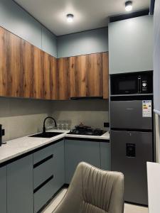 cocina con armarios de madera, fregadero y fogones en Little Comfort Home, en Karakol