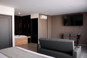 ein Schlafzimmer mit Bett und Sofa sowie ein Badezimmer in der Unterkunft Hotel Del Centro HC in Tepatitlán
