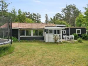 a small black house with a yard and a house at Holiday Home Raika - 1-5km from the sea by Interhome in Tengslemark