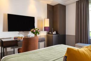 a hotel room with a bed and a desk and a television at Hotel Villa Saxe Eiffel in Paris