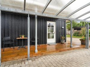 a black house with a wooden deck with a table at Holiday Home Brune - 330m from the sea by Interhome in Sæby