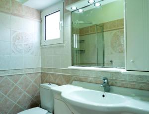 a bathroom with a sink and a toilet and a mirror at Haraki Beach Mediterranean Retreat in Haraki +22 photos