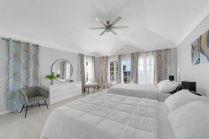 a white bedroom with a large bed and a ceiling fan at Nevas Estate w Hot Tub 10 ppl in St Mary