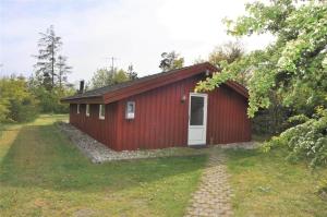 a red shed with a white door in a yard at 30054-Ulfborg-Lathyrusvej-307 in Vang