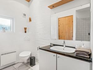 a white bathroom with a toilet and a sink at Holiday Home Takenya - 350m to the inlet by Interhome in Esbjerg