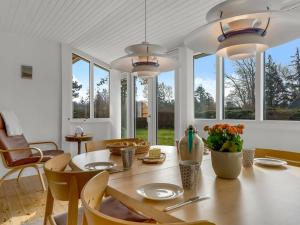 a dining room with a table and chairs and windows at Holiday Home Andrine - 100m from the sea by Interhome in Nakskov