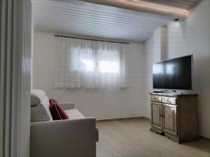 a living room with a couch and a flat screen tv at El Zirum Boscoverde in Sottoguda
