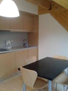 cocina con mesa negra y sillas blancas en Casa de los Beneficiados en Roncesvalles
