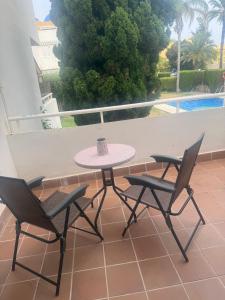 einen Tisch und Stühle auf einem Balkon mit Poolblick in der Unterkunft Vera Armony Natura FKK in Playas de Vera