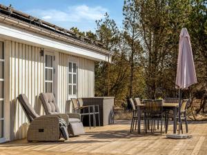 a patio with a table and chairs and an umbrella at Holiday Home Toska - 3km from the sea by Interhome in Blokhus +22 photos