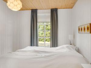 een slaapkamer met een wit bed en een raam bij Holiday Home Toska - 3km from the sea by Interhome in Blokhus +22 foto's