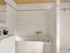 een wit bad in een badkamer met witte tegels bij Holiday Home Toska - 3km from the sea by Interhome in Blokhus